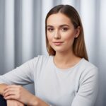 Młoda kobieta w jasnej koszuli na neutralnym tle, naturalne oświetlenie, realistyczne zdjęcie portretowe